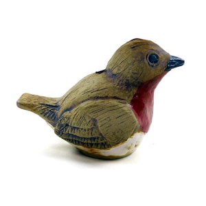 May include: A ceramic robin figurine with a brown, green, and white body and a red breast.