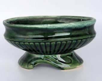 May include: A green ceramic planter with a fluted design and a pedestal base.