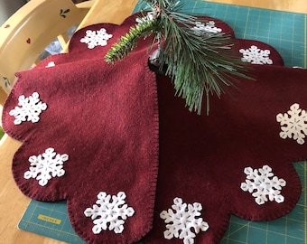 Primitive snowflake tree skirt in dark red background with off white snowflakes in the scallops.(hole in the center with a slit)