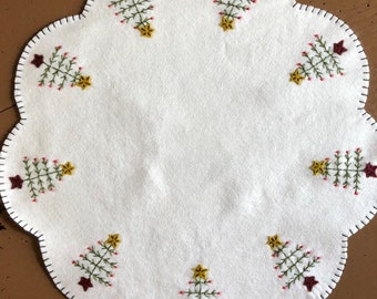 Primitive feather tree candle mat with an off white background