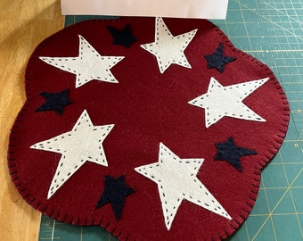 Patriotic/ Americana/ 4th of July candle mat with a maple leaf red background and off white large stars and navy small stars.