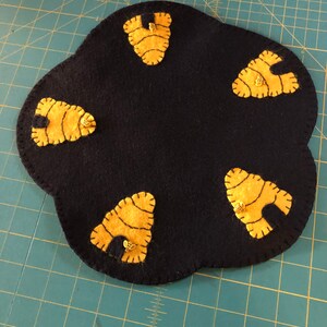 May include: A black felt beehive-shaped doormat with five yellow felt beehives attached to it.
