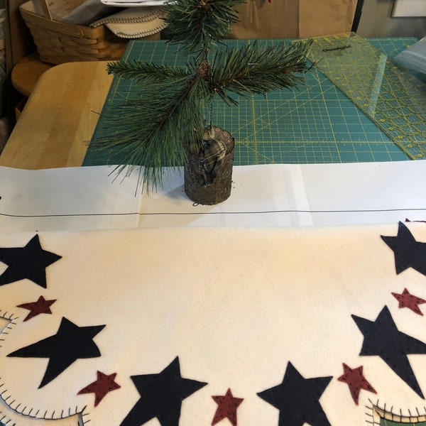 Primitive patriotic tree skirt off white background with navy large stars and dark red small stars