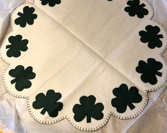 Shamrock table mat measuring 18 or 22 inches off white background with dark green shamrocks in the scallops