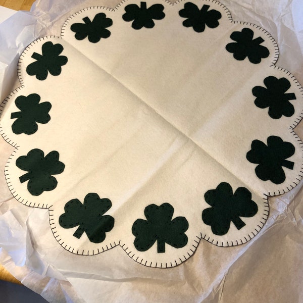 Shamrock table mat measuring 18 or 22 inches off white background with dark green shamrocks in the scallops