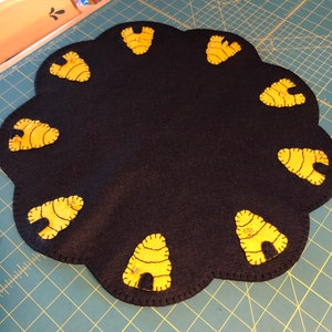 May include: A black felt table runner with a scalloped edge and yellow beehive designs.