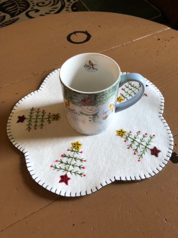 Feather tree candle mat shown on an off white background measuring 12 inches.
