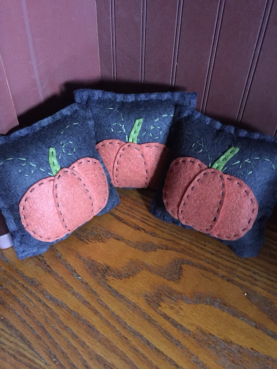 Bowl filler set of 3 pumpkin pillows with black background and orange pumpkins.