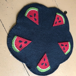 Primitive watermelon candle mat measuring 12 inches across with a black background.