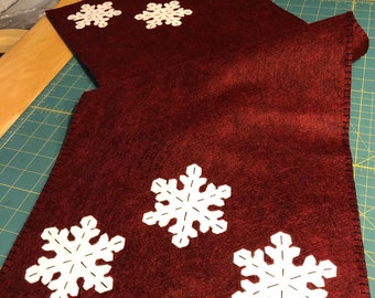 Primitive snowflake table runner with a dark red background and 3 off white snowflakes on each end