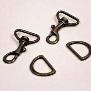 May include: Four antique brass metal hardware pieces: two swivel clasps and two D-rings.