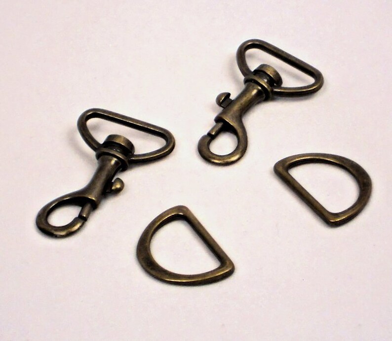 May include: Four antique brass metal hardware pieces: two swivel clasps and two D-rings.