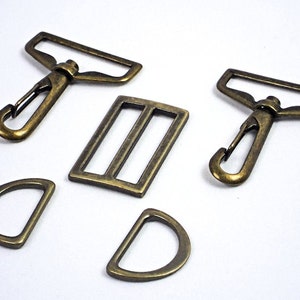 May include: A set of five antique gold metal hardware pieces, including two swivel clasps, a buckle, and two D-rings.
