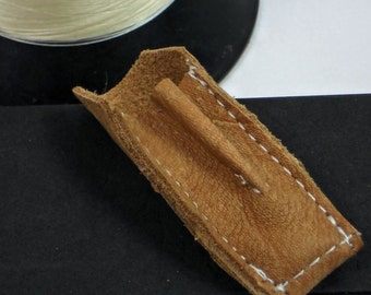 May include: A close-up of a brown leather strap with white stitching. The strap is folded in half and has a small hole in the center.
