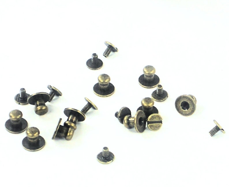May include: A collection of antique gold-toned metal furniture knobs with screws. The knobs have a round base and a raised dome-shaped top.