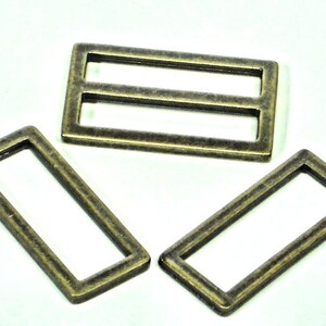 May include: Three antique gold metal slider buckles. The buckles are rectangular with a single or double opening.