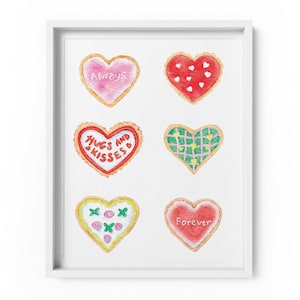 May include: A framed print featuring six heart-shaped cookies with various designs and text. The cookies are decorated with pink, red, green, and yellow icing. Text includes "Always", "Hugs and Kisses", and "Forever".