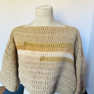 May include: A beige crocheted sweater with a horizontal stripe pattern in shades of brown and cream.