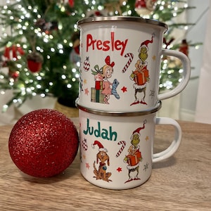 Pu&ograve; includere: Due tazze di smalto bianco con disegni a tema natalizio. La tazza superiore ha il nome "Presley" e la tazza inferiore ha il nome "Judah". Entrambe le tazze presentano un personaggio verde del Grinch, una canna di zucchero rosso e bianca e un ornamento natalizio rosso e bianco.