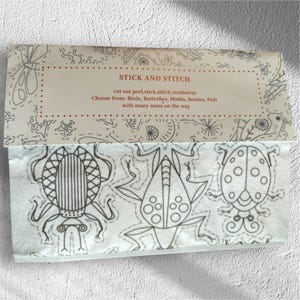 May include: A pack of "STICK AND STITCH" designs, featuring instructions and design options. The image shows three insect outlines: a beetle, a frog-like insect, and a ladybug, all in black on a white background.