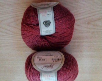 May include: Two skeins of deep red yarn with a subtle heathered texture. Each ball features a white paper label with the brand name Topland, color code M506, and dye lot 008 printed in black text. The yarn appears soft and loosely wound.