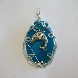 May include: A silver wire wrapped pendant featuring a blue agate stone with a silver dolphin charm.