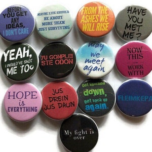 May include: A set of 11 round button pins with various colorful backgrounds and text. The text on the pins includes phrases like "From the ashes we will rise", "Hope is everything", "May we meet again", and "Now this can work with".