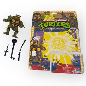 Figura de las Tortugas Ninja Adolescentes Mutantes de Tokka de 1991 con 3 accesorios y tarjeta de archivo