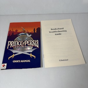 Pode incluir: A imagem mostra um manual do usuário "Prince of Persia Collection" e um "Guia de solução de problemas Brøderbund". A capa do manual apresenta uma figura no ar, uma paisagem urbana e espadas cruzadas. O guia é branco com texto preto.