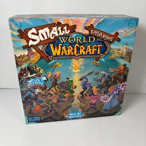 Op de afbeelding: Een bordspeldoos met de titel "Small World of Warcraft" met een fantasie-illustratie. De doos heeft een blauwe achtergrond met verschillende personages en landschappen. De logo's van Blizzard en Days of Wonder zijn zichtbaar.