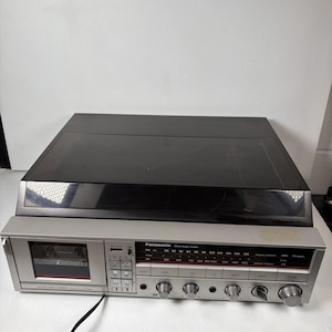 May include: A vintage Panasonic stereo music system with a silver face and black top. The system includes a cassette player, radio tuner, and control knobs. The radio dial displays FM frequencies.