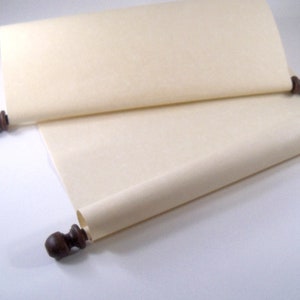 May include: A blank scroll with wooden dowels at each end. The scroll is rolled up and tied with a ribbon. The scroll is made of a light cream-colored paper.