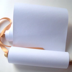 May include: A rolled white paper scroll with a gold ribbon and wooden finials. The scroll is unrolled, revealing a blank surface for writing or drawing. The ribbon is looped around the scroll.