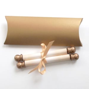 May include: Two ivory scrolls tied with a satin ribbon and topped with gold-colored finials. The scrolls are packaged in a gold envelope.