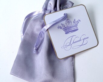 May include: A lavender satin drawstring bag with a matching ribbon and a small white card with a purple crown and the text "Thank you".