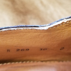 May include: Close-up of the inside of a brown leather shoe with the text "R 269 7 0" printed on the insole.
