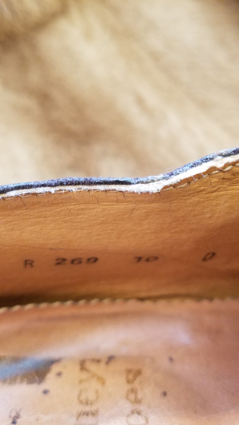 May include: Close-up of the inside of a brown leather shoe with the text "R 269 7 0" printed on the insole.
