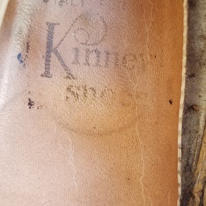 May include: Close-up of the inside of a brown leather shoe with the text "Made in Italy" and "K" with a circle around it.