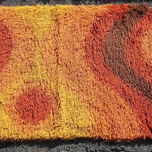 May include: A shaggy rug with a geometric pattern in shades of brown, orange, and yellow.