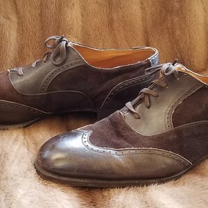 May include: A pair of brown leather and suede lace-up shoes with wingtip detailing.