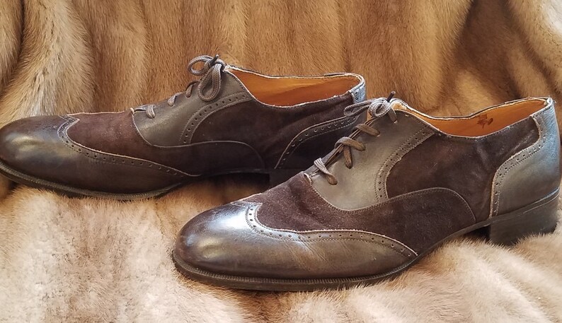 May include: A pair of brown leather and suede lace-up shoes with wingtip detailing.