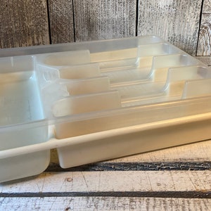 Pode incluir: Uma bandeja de talheres de pl&aacute;stico transparente com v&aacute;rios compartimentos para organizar a prataria. A bandeja &eacute; de cor branco sujo e tem formato retangular com v&aacute;rias ranhuras e divis&oacute;rias. &Eacute; projetada para caber dentro de uma gaveta de cozinha.