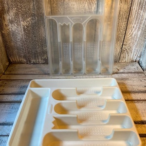 Pode incluir: Duas bandejas de talheres de pl&aacute;stico. A bandeja superior &eacute; transparente e a inferior &eacute; esbranqui&ccedil;ada. Ambas as bandejas t&ecirc;m v&aacute;rios compartimentos para organizar os talheres. A bandeja transparente est&aacute; posicionada acima da esbranqui&ccedil;ada.