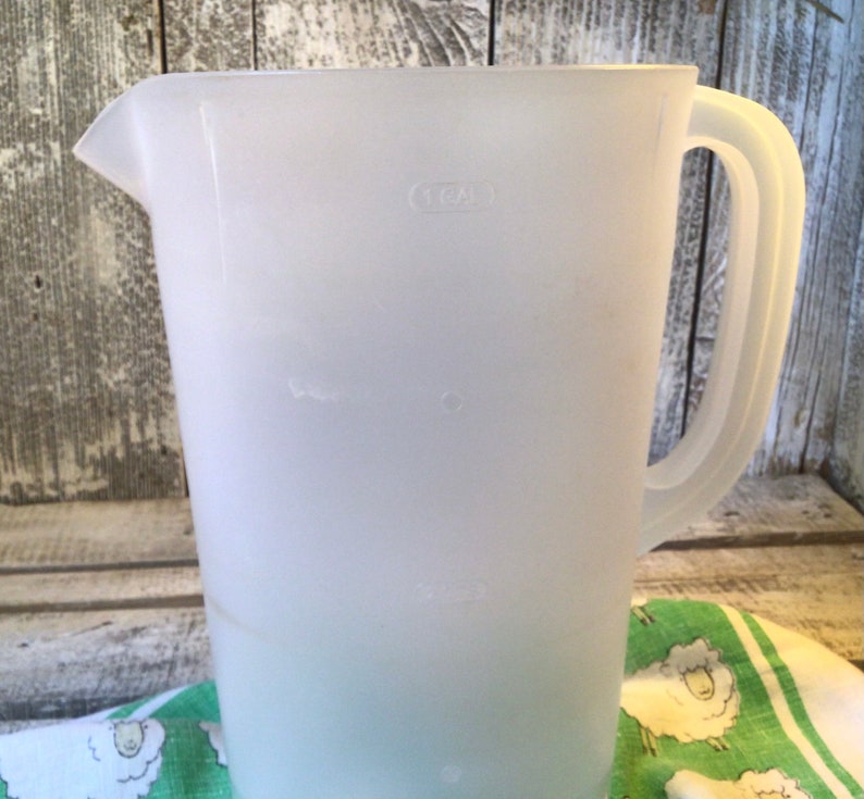 Pu&ograve; includere: Una caraffa in plastica traslucida e semitrasparente dotata di manico laterale e beccuccio. Il corpo della caraffa presenta tacche di misurazione in rilievo, inclusa un'etichetta chiara che indica una capacit&agrave; di 1 GAL vicino al bordo superiore.