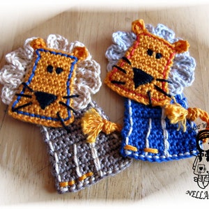 Könnte beinhalten: Zwei gehäkelte Löwen-Ornamente mit einer weißen Mähne, einem orangefarbenen Gesicht und schwarzen Augen. Ein Löwe trägt ein blau-weiß gestreiftes Outfit mit gelbem Besatz. Der andere Löwe trägt ein grau-weiß gestreiftes Outfit mit gelbem Besatz. Beide Löwen haben einen gelben Quasten.