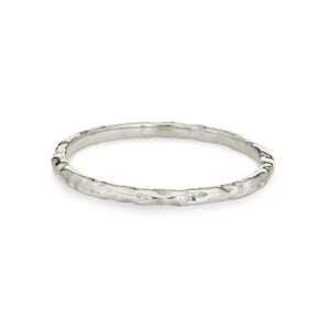 May include: A thin silver band ring with a textured, hammered finish.