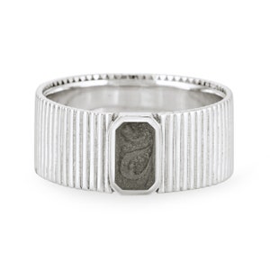 May include: A silver ring with a textured band and a rectangular, gray stone set in the center.