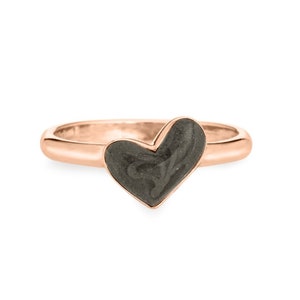 May include: A rose gold ring with a heart-shaped grey stone. The stone has a swirling pattern.