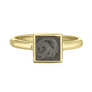 May include: A gold band ring with a square gray stone set in a gold frame.