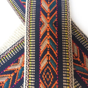 Puede incluir: Primer plano de una tela negra tejida con patrones geom&eacute;tricos coloridos. La tela tiene un dise&ntilde;o de hilo marr&oacute;n, naranja, verde y amarillo.